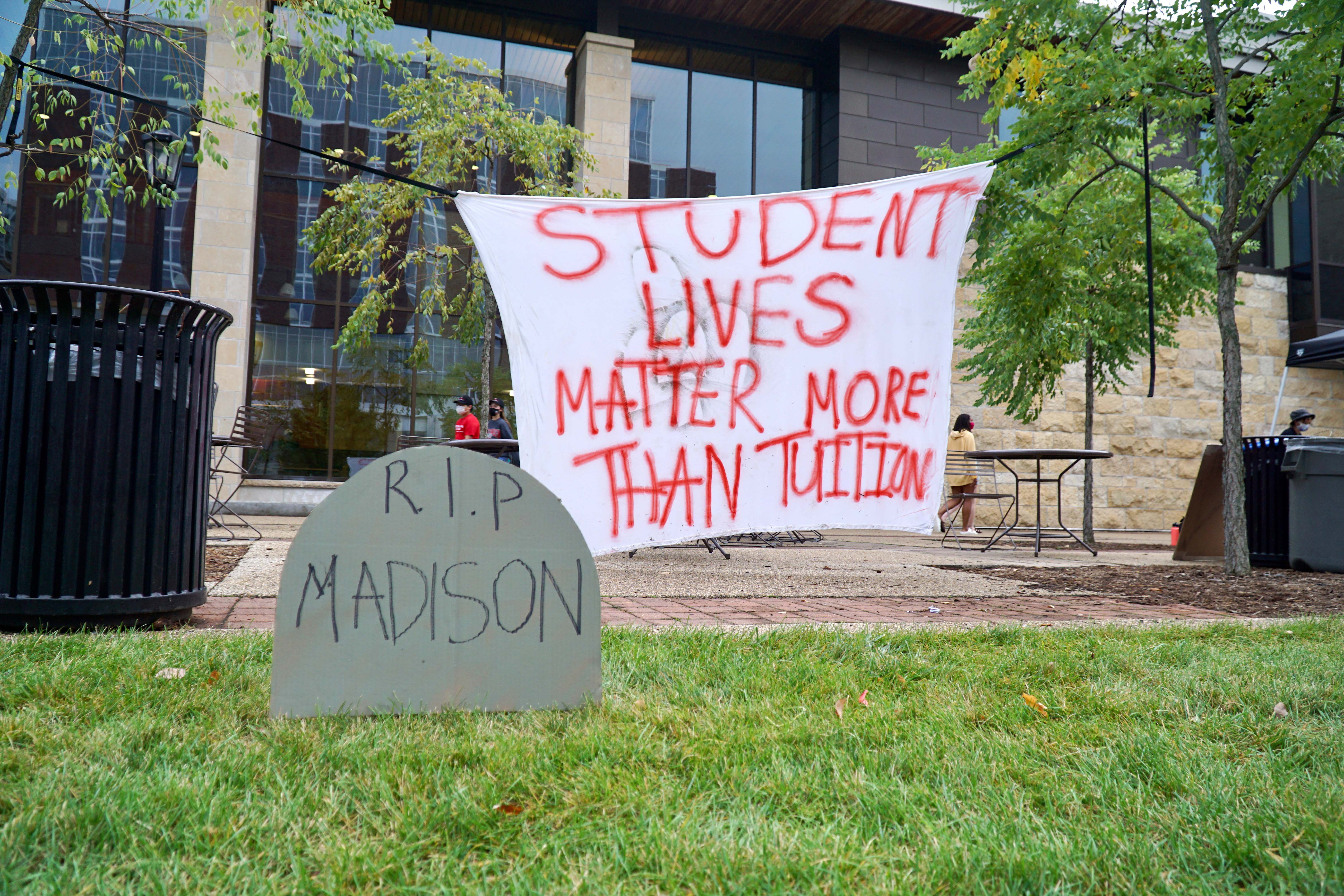 Protest signs reading 'Student lives matter more than tuition' and 'R.I.P. Madison.'